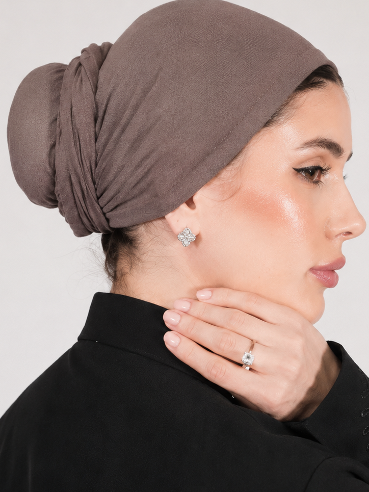 Woman wearing a brown headscarf against a plain background